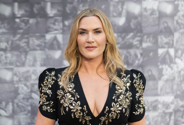 Kate Winslet in a black dress decorated with gold flowers smiles on the red carpet at the premiere of Lee